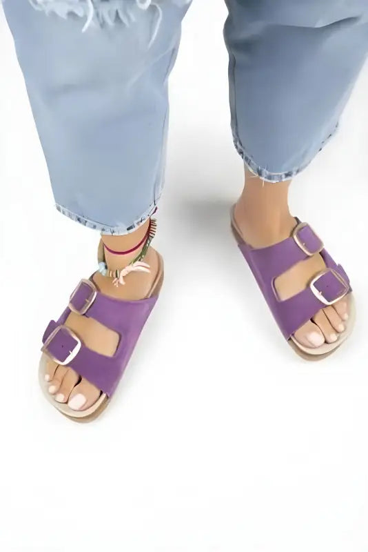 Purple double-buckle sandals with cork footbeds worn with cropped jeans.