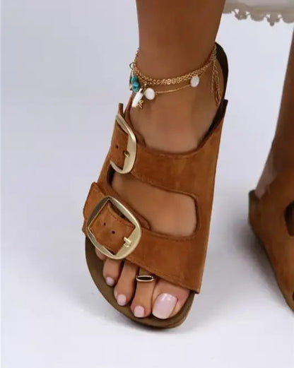 Brown leather sandal with double buckle straps and an ankle bracelet featuring turquoise beads.