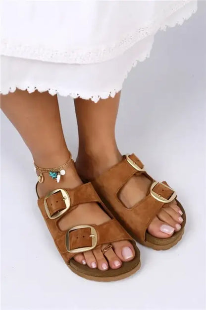 Brown leather sandals with gold buckles and a cork-style footbed.