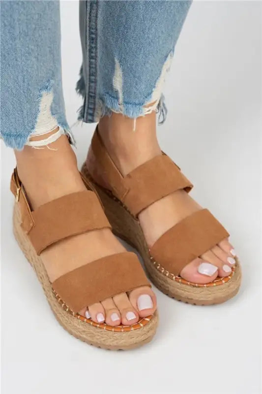 Tan leather sandals with espadrille soles and double straps worn with distressed jeans.