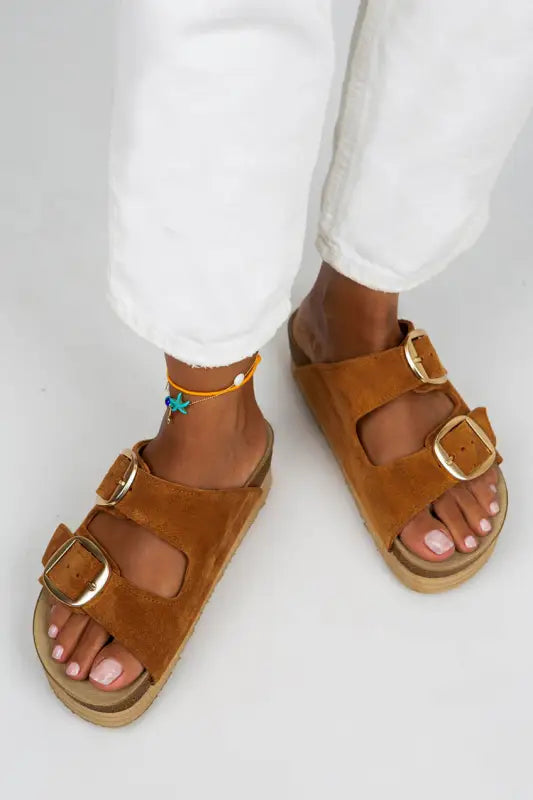 Brown leather sandals with buckle straps and a flat sole.