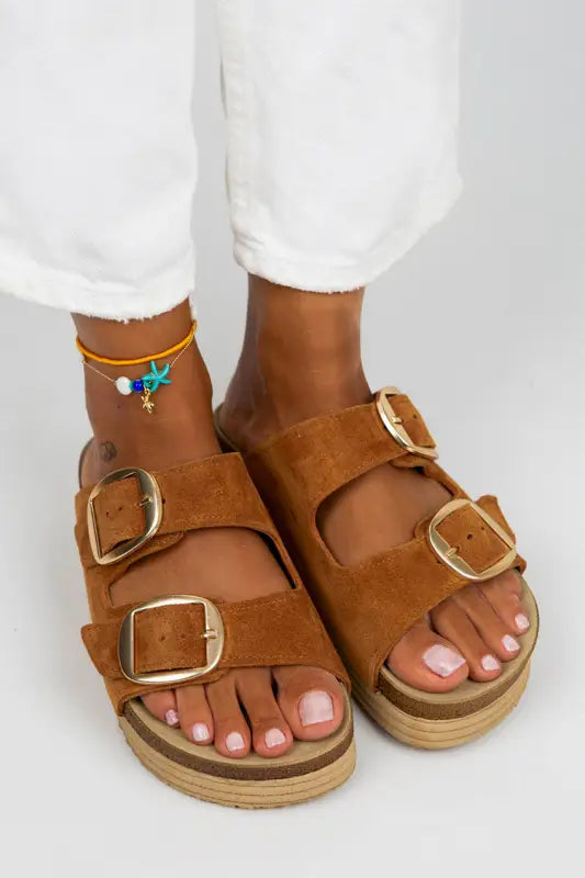 Brown leather double-buckle sandals with a cork-style platform sole.