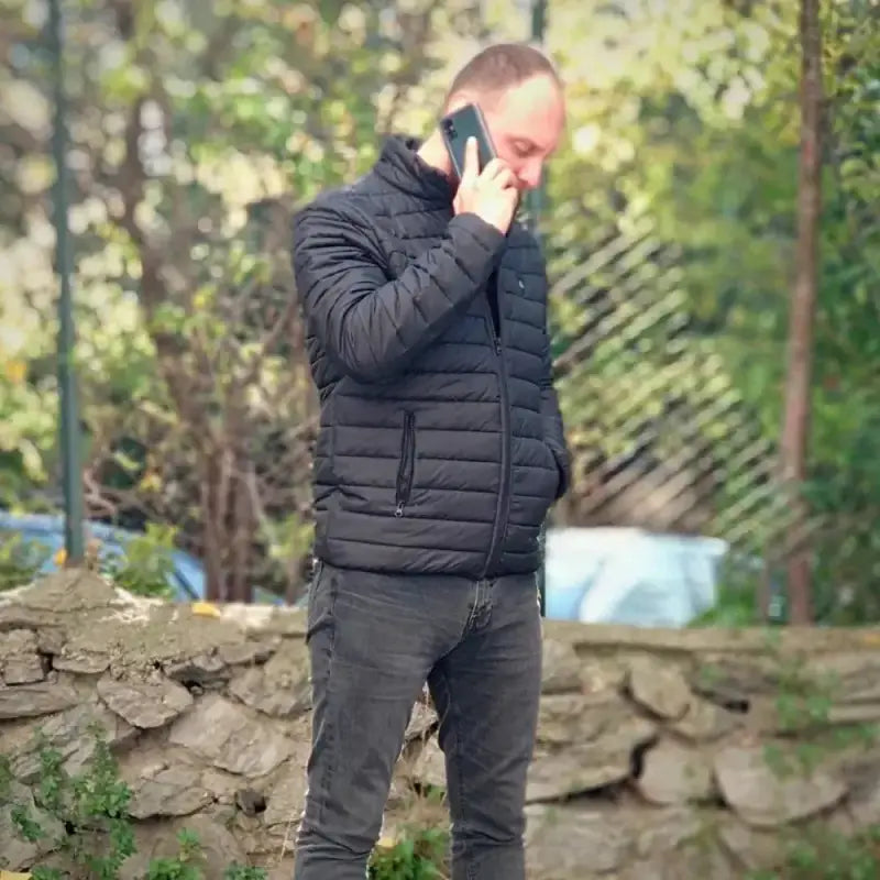 Person in a black puffer jacket talking on a phone.