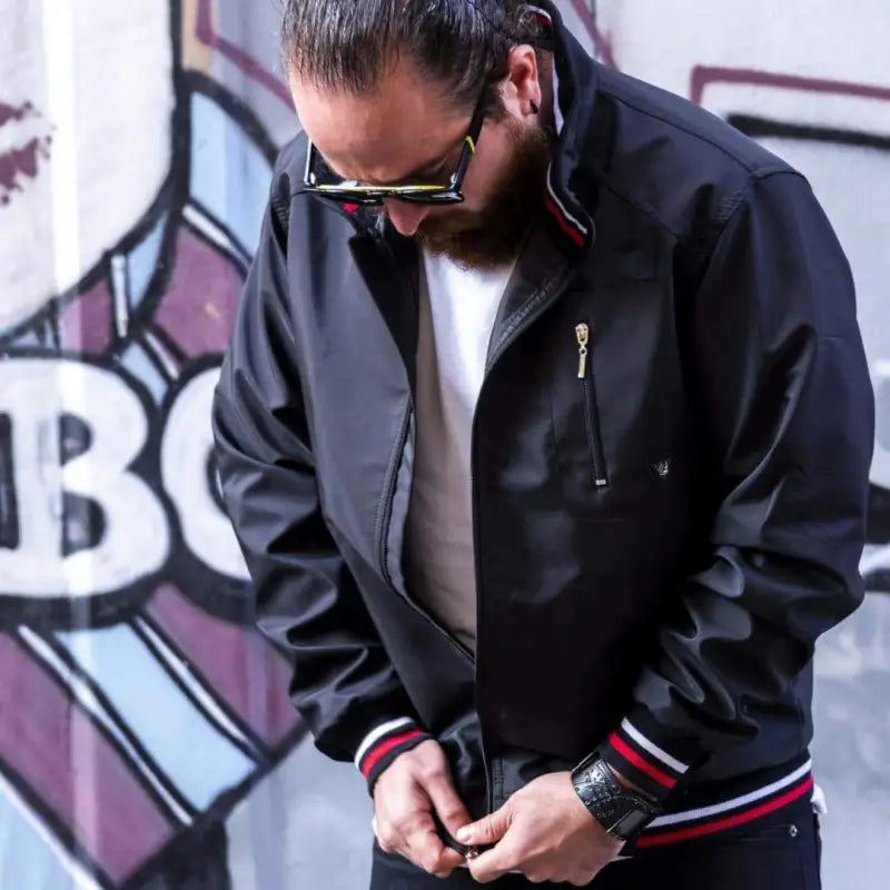 Black bomber jacket with red and white striped ribbing at the cuffs.