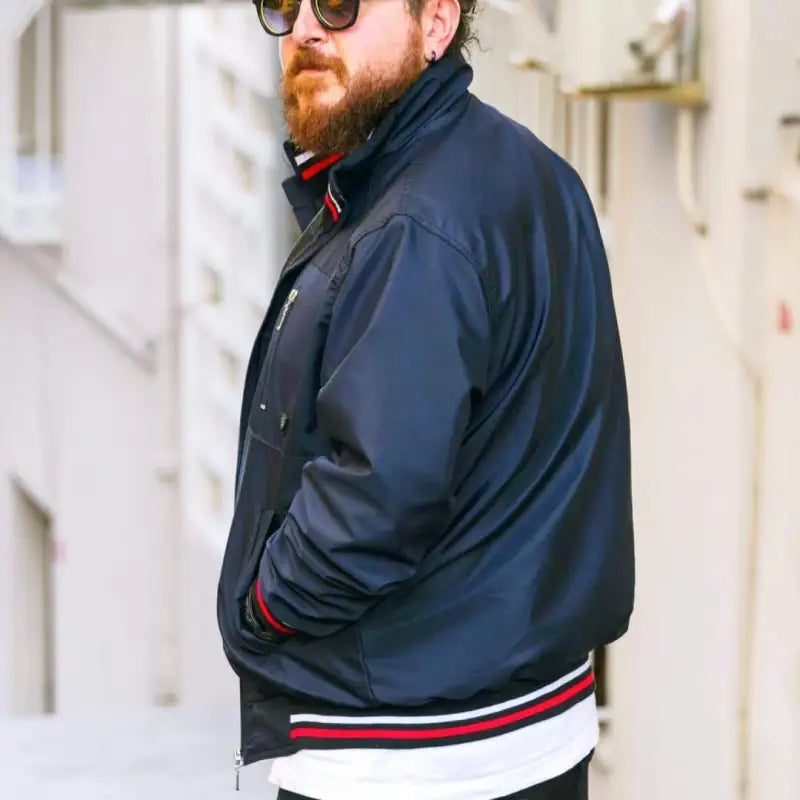 Navy blue bomber jacket with red and white striped ribbing at the waist.