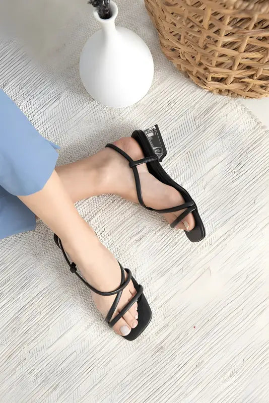 Black strappy sandals with thin crisscrossing straps and an ankle strap.