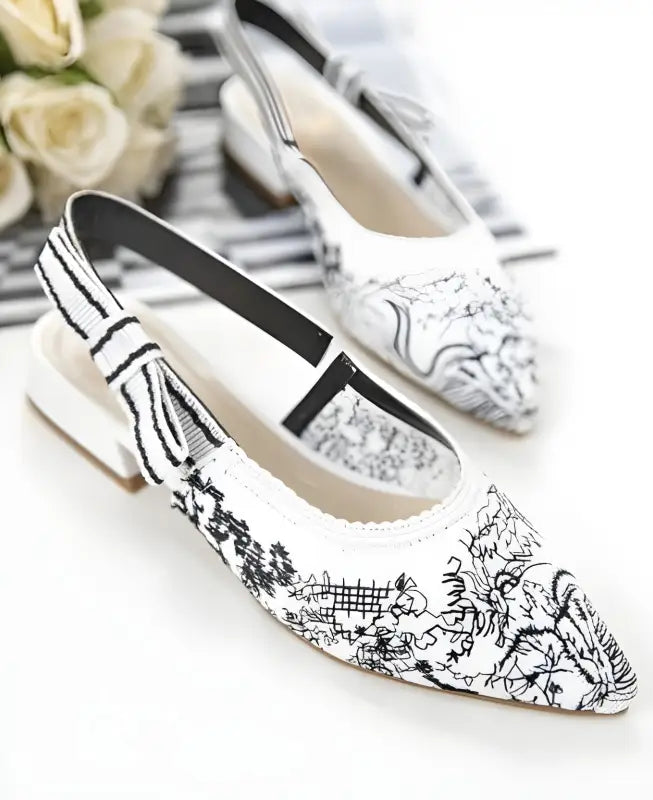 White flats with black toile-style print and a pointed toe design.