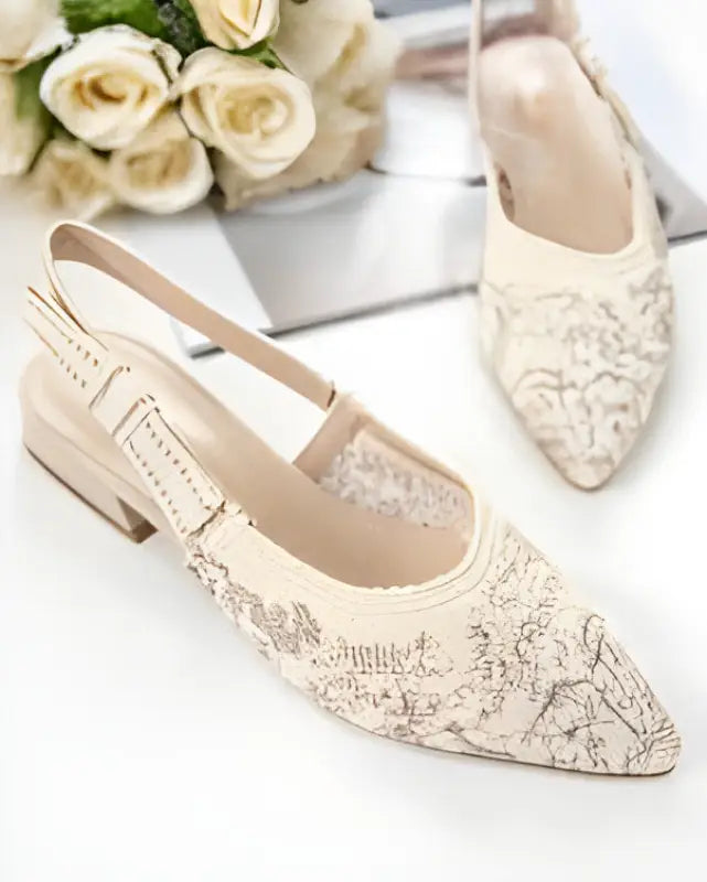 Cream-colored lace flats with delicate floral embroidery and a low heel.