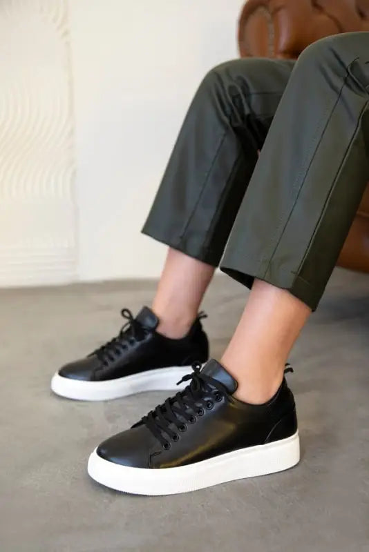 Black leather sneakers with white platform soles and laces.