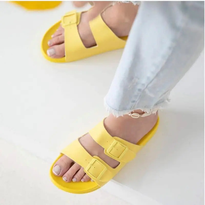 Yellow double-strap slide sandals with buckle closures.