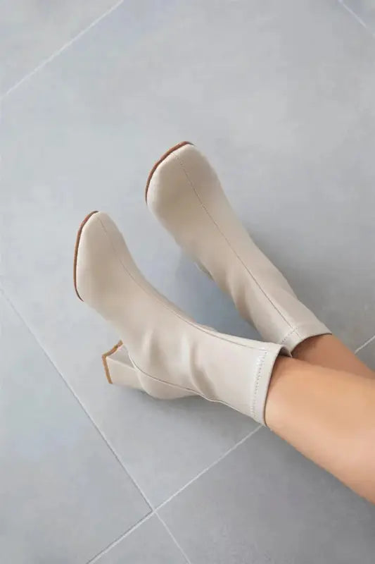 Cream-colored leather boots with a curved heel.