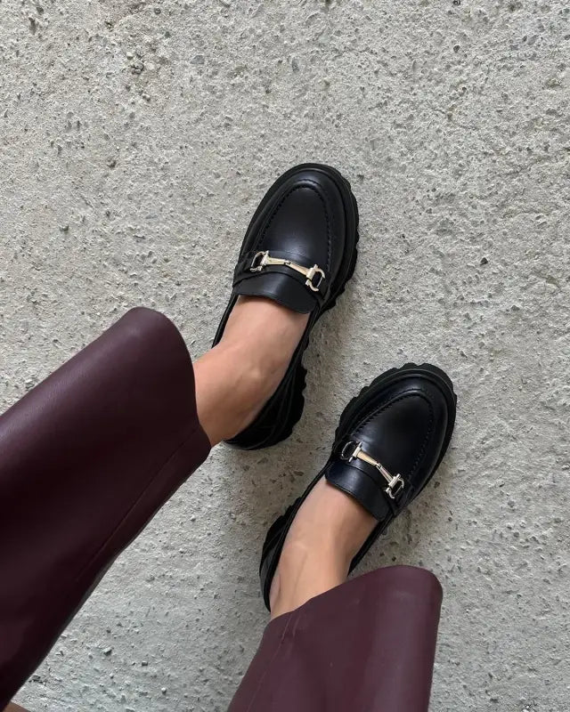 Black leather loafers with metal horsebit hardware.