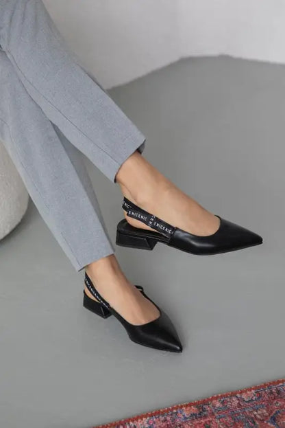 Black pointed-toe slingback flats with a low heel and text detailing on the strap.