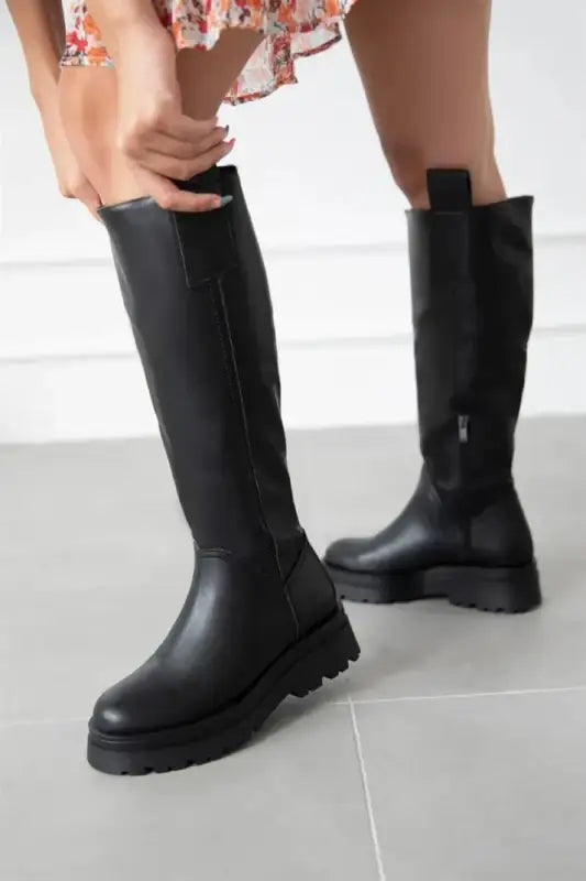 Black leather knee-high boots with chunky platform soles.