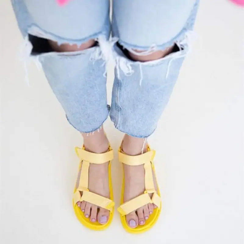 Yellow Teva-style sandals paired with distressed light blue jeans.