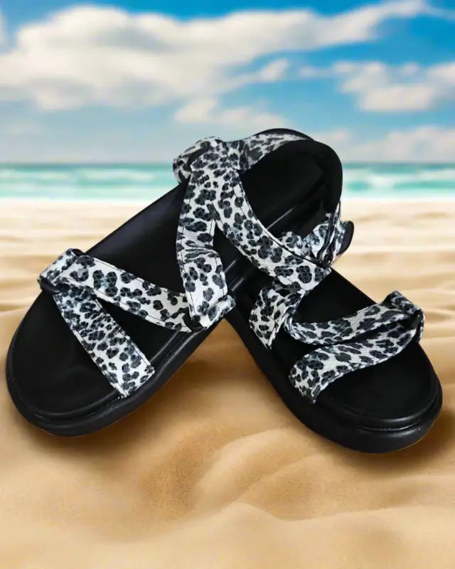 Black sandals with white leopard print straps.