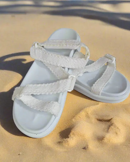 White braided-strap sandals with a flat sole.