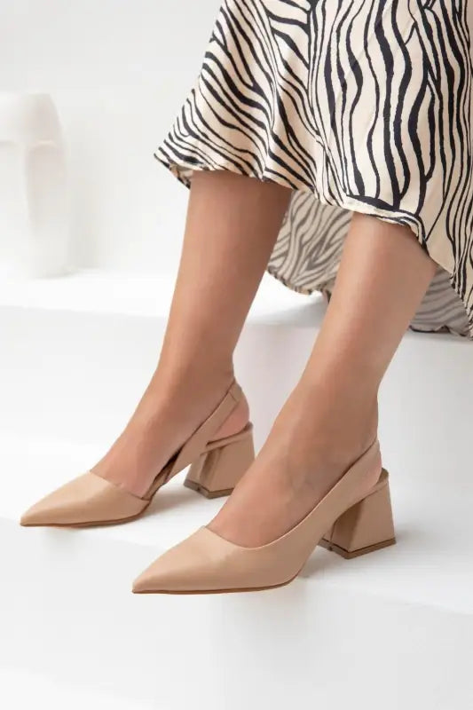 Nude-colored pointed-toe block heel pumps.