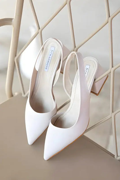 White pointed-toe slingback heels with a slim heel.