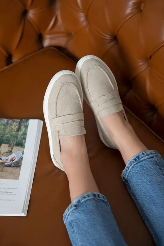 Beige suede loafers worn with blue jeans.