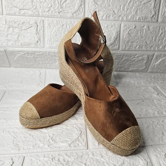 Brown suede espadrille wedges with ankle straps and jute rope soles.