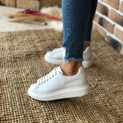 White platform sneaker with laces worn with frayed-hem jeans.