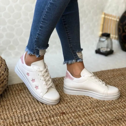 White sneakers with pink floral details and a platform sole.