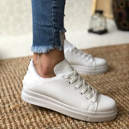 White leather lace-up sneaker with a flat sole.